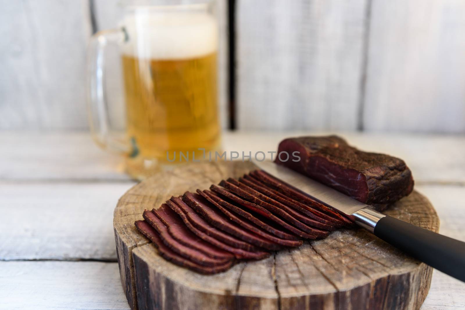 pastrami beer in a glass knife on a wooden table