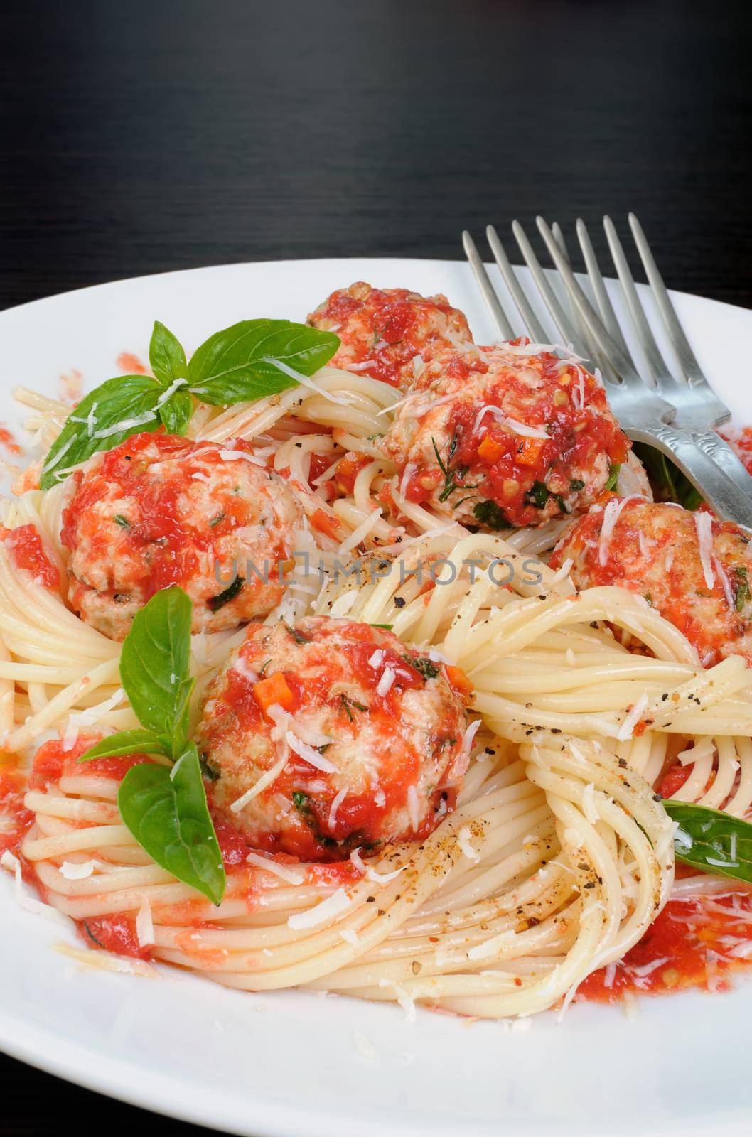 Pasta in tomato gravy with meatballs sprinkled Parmesan and basil