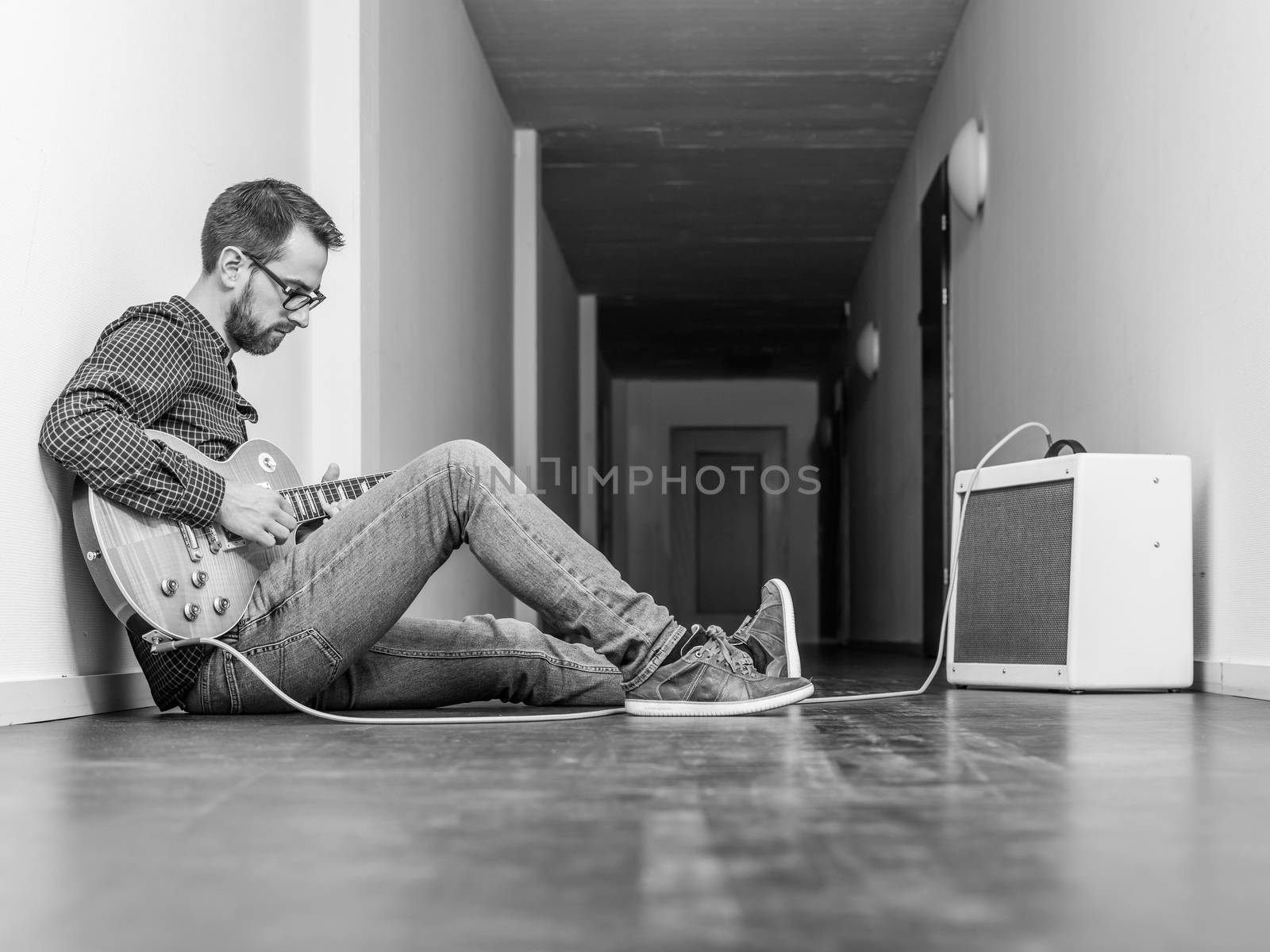 Man playing an electric guitar in a hallway by sumners