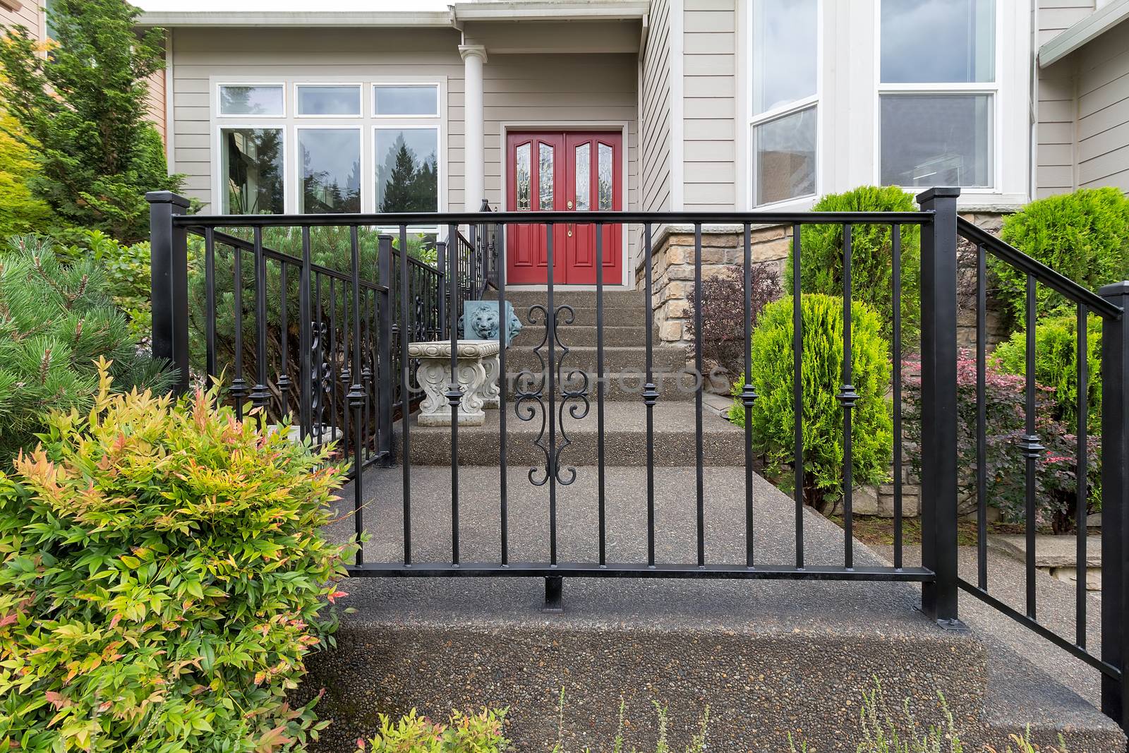 House front entrance with wrought iron railings on stairs with plants landscaping