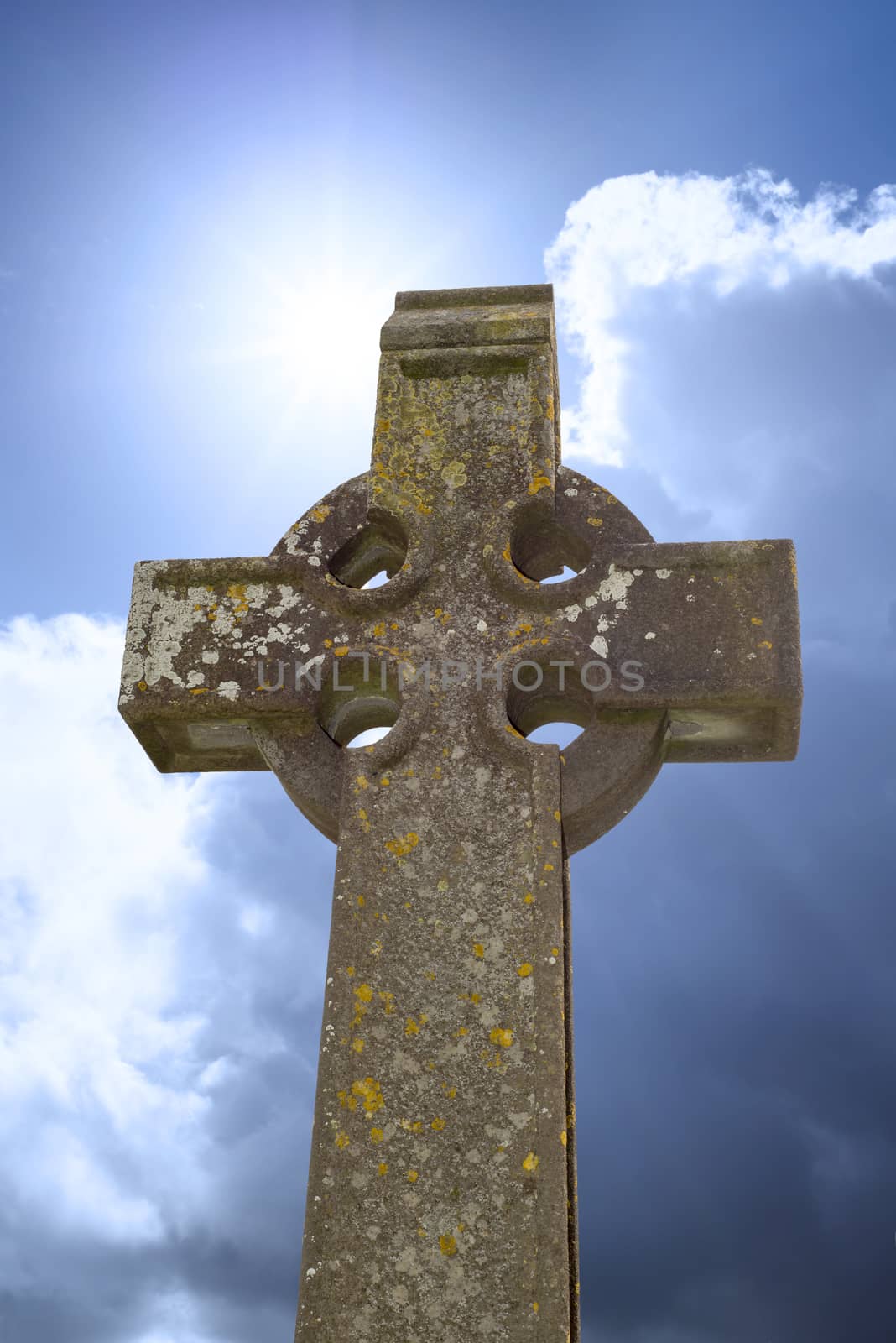 sunshine over celtic cross at ancient graveyard by morrbyte