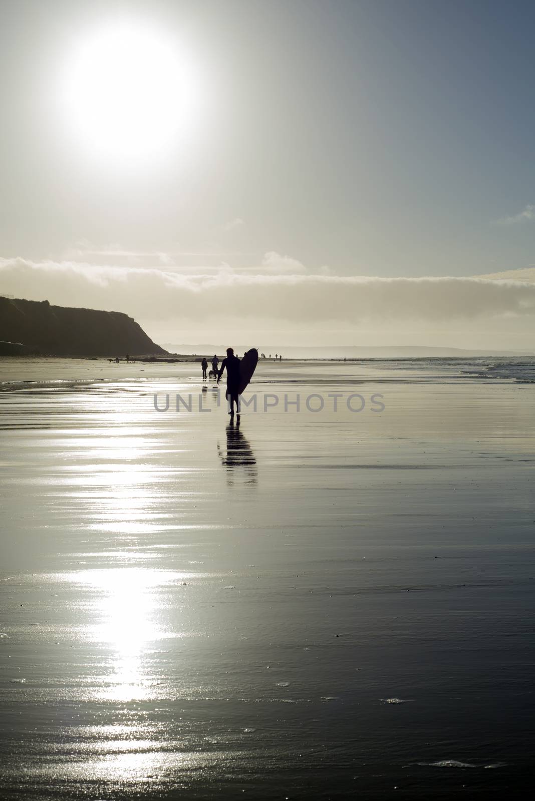silhouette of surfer and people out for a walk as the sun sets in Ballybunion county Kerry Ireland
