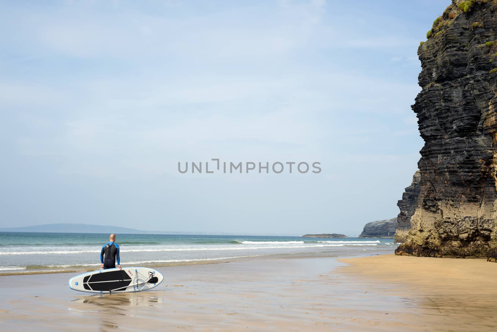 surfer standing with board on ballybunion beach in the wild atlantic way
