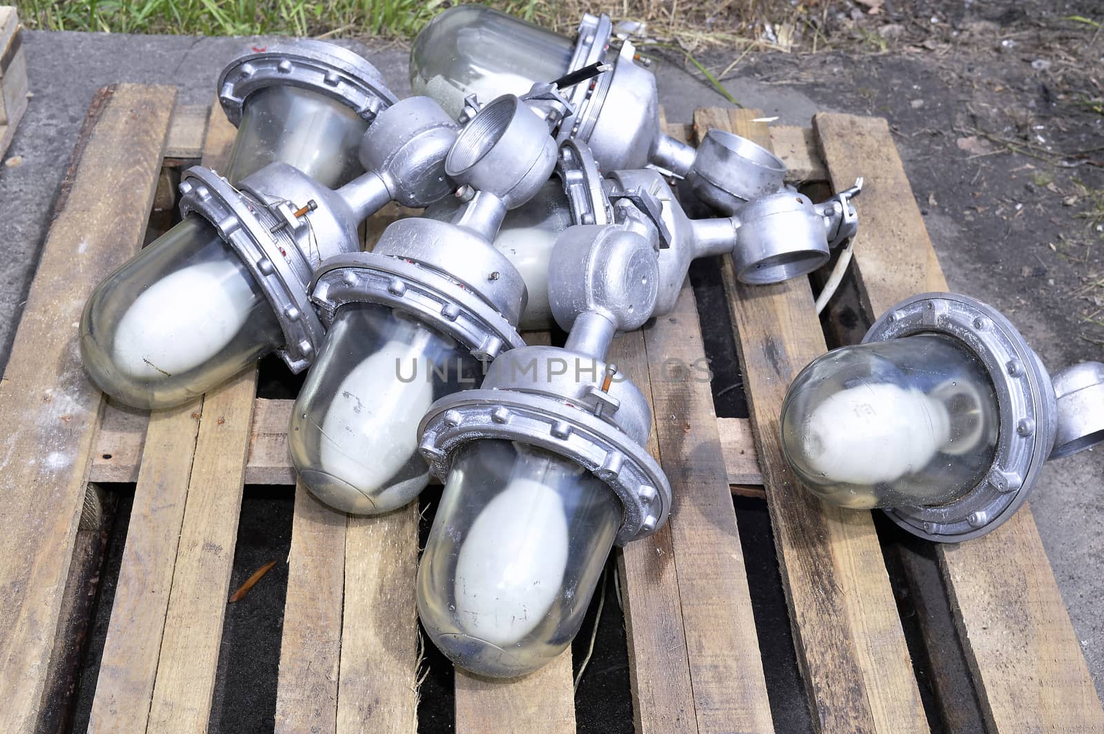 Used in the production of waste lamps are stacked on a wooden pallet on the floor.