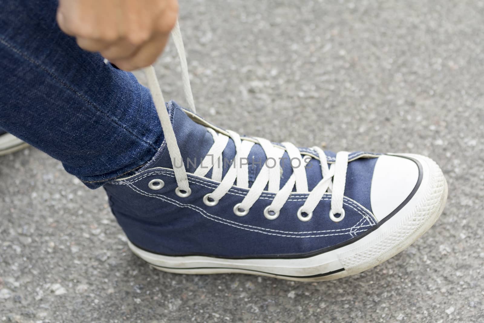 Hands girl with beautiful manicure knotted the laces on your shoelace.