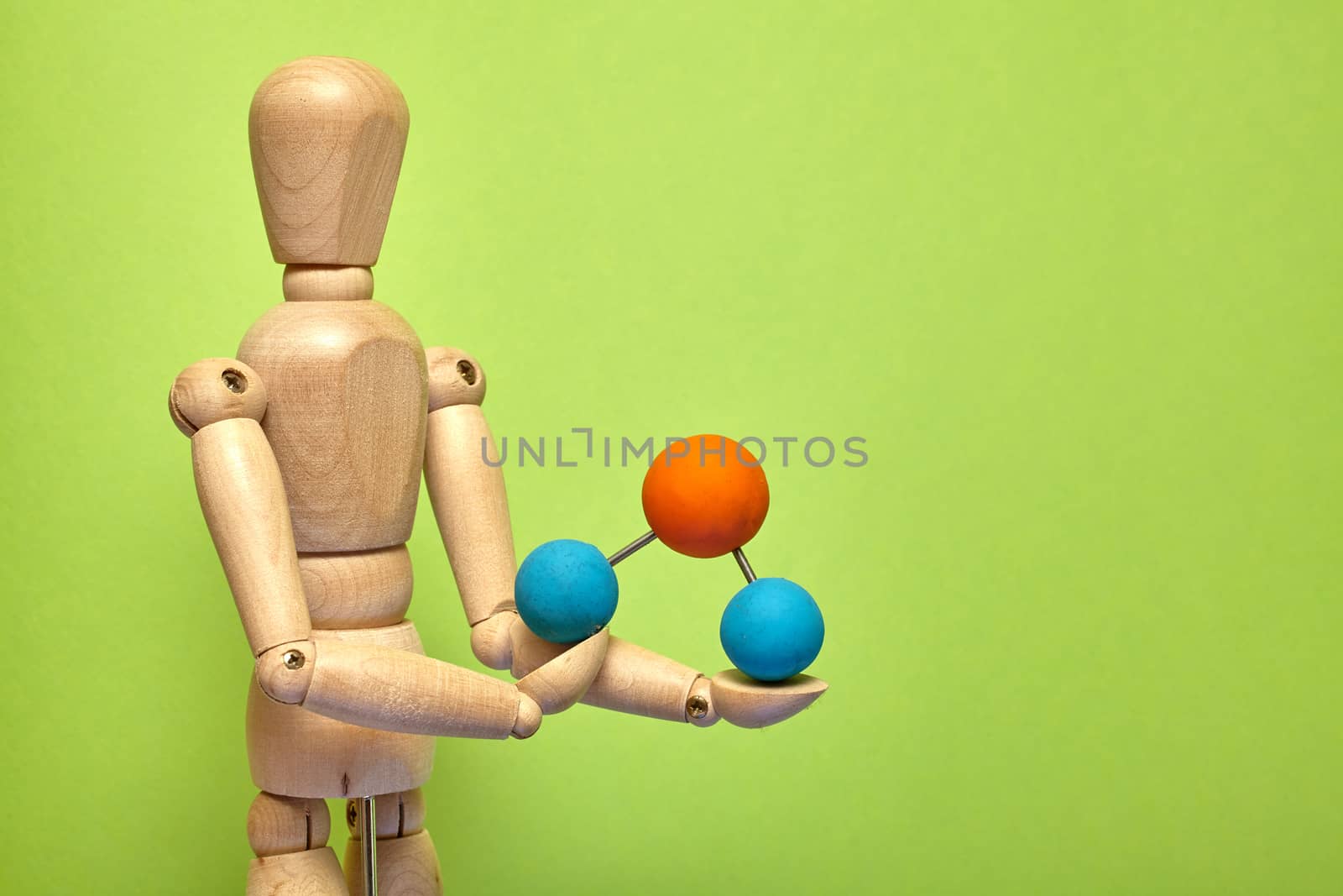 Wooden puppet with molecule on green background