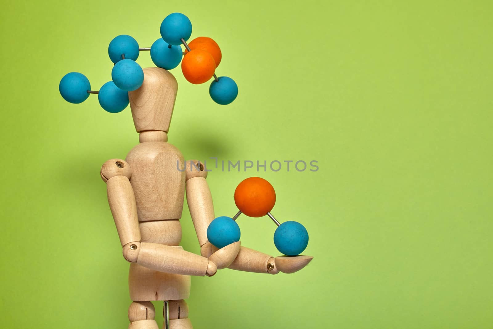 Wooden puppet with molecule on green background