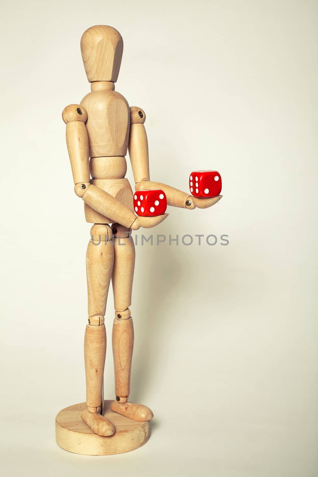 Wooden puppet holds dice on white background