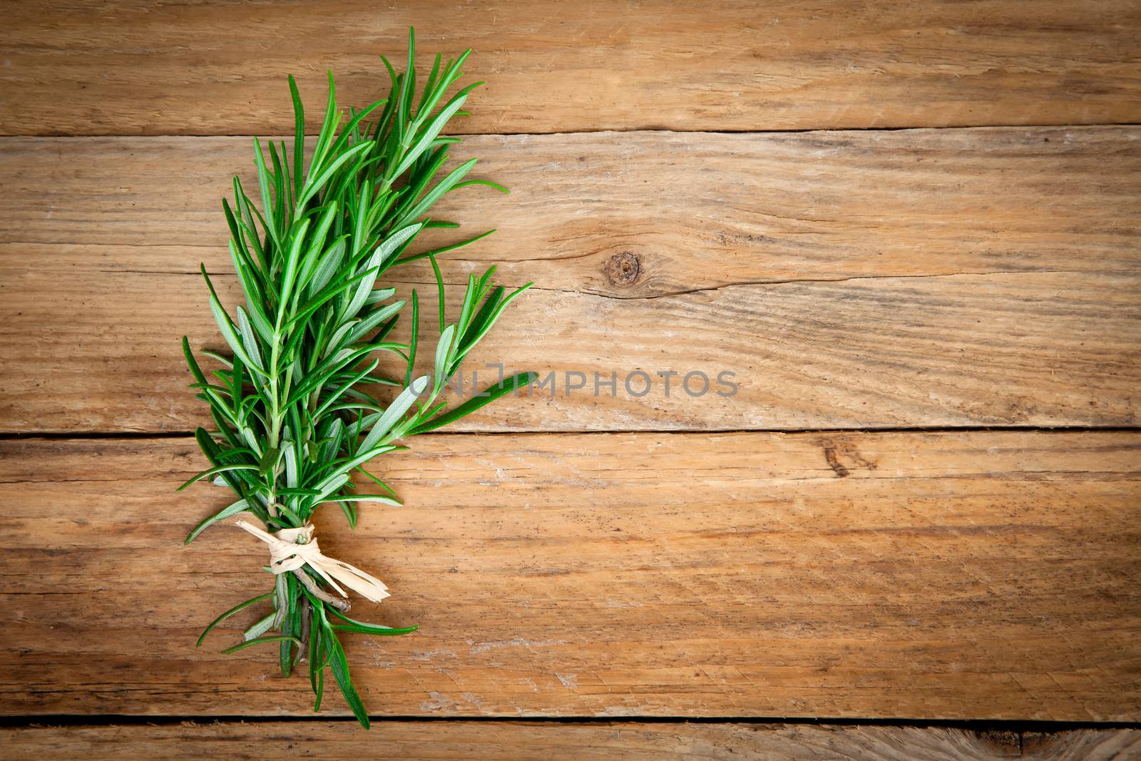 Rosemary bound on a wooden background. by motorolka