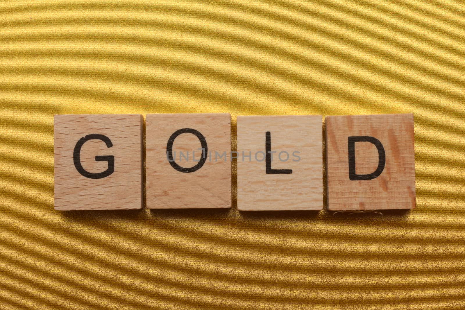 Wooden letters spelling GOLD on yellow background