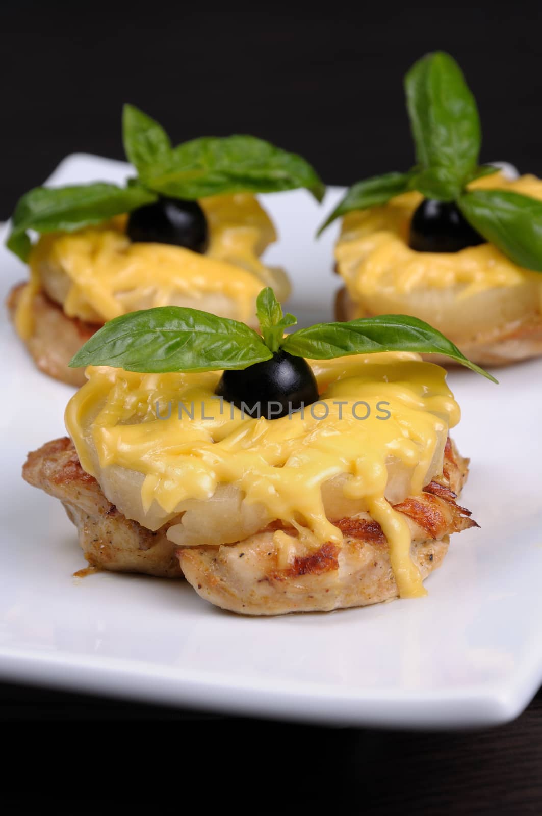 A piece of chicken with pineapple and cheese with olives and basil