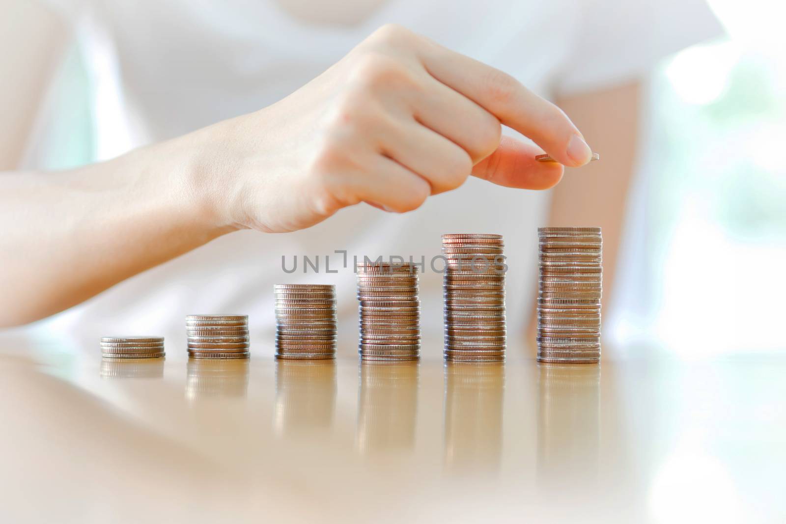 Savings, business woman stacking coins into increasing columns