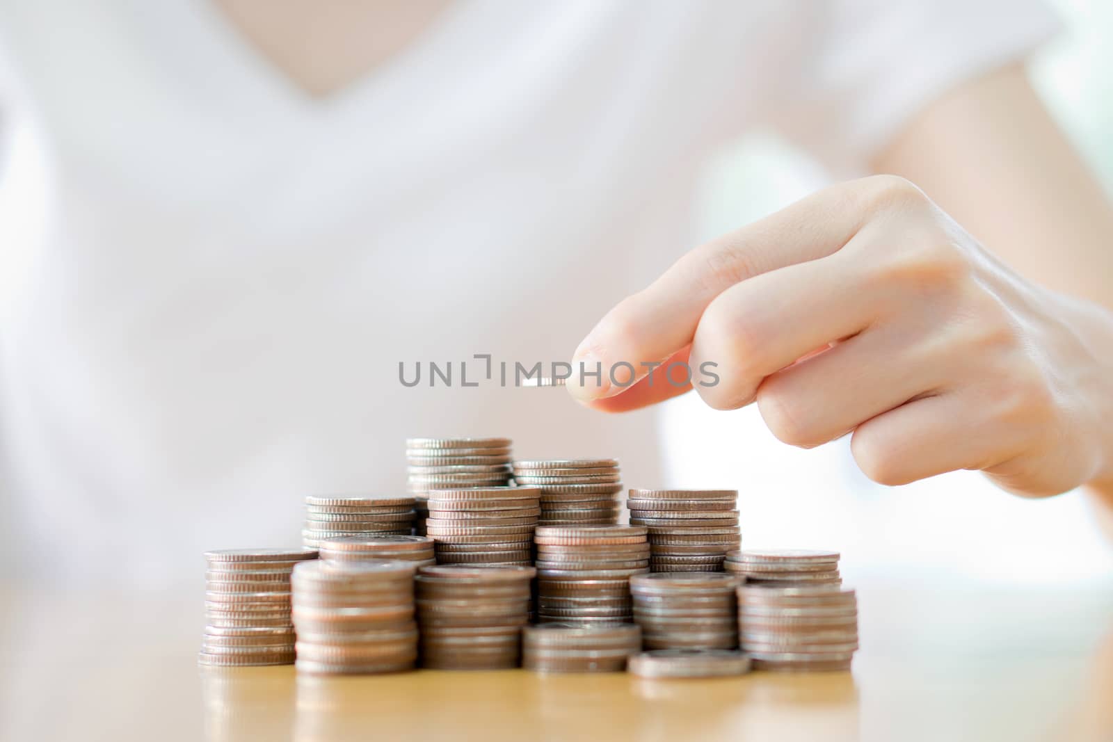 Close up of female hand stacking gold coins isolated on white background