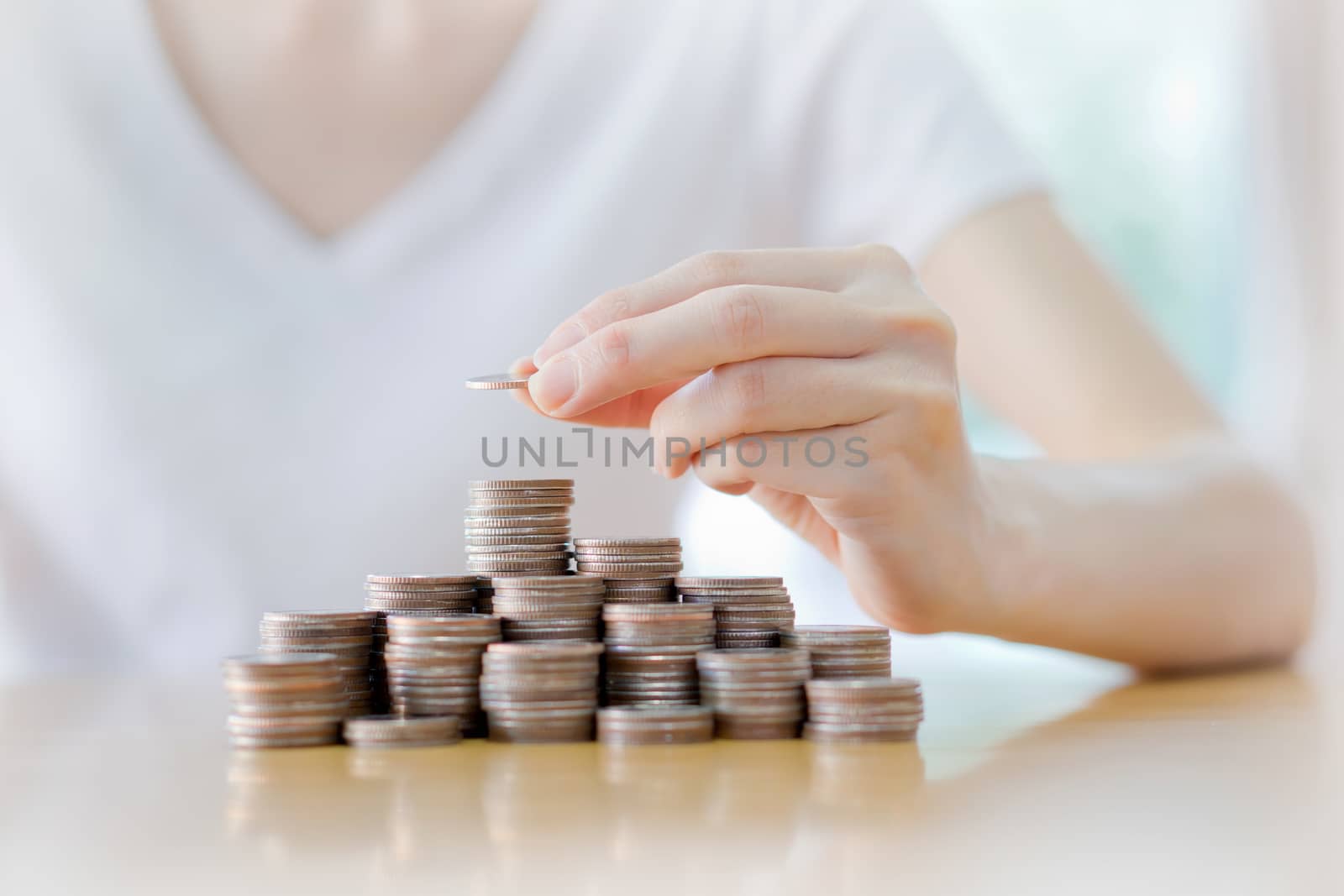 Close-up Of Businesswoman Putting Coin To Rising Stack Of Coins