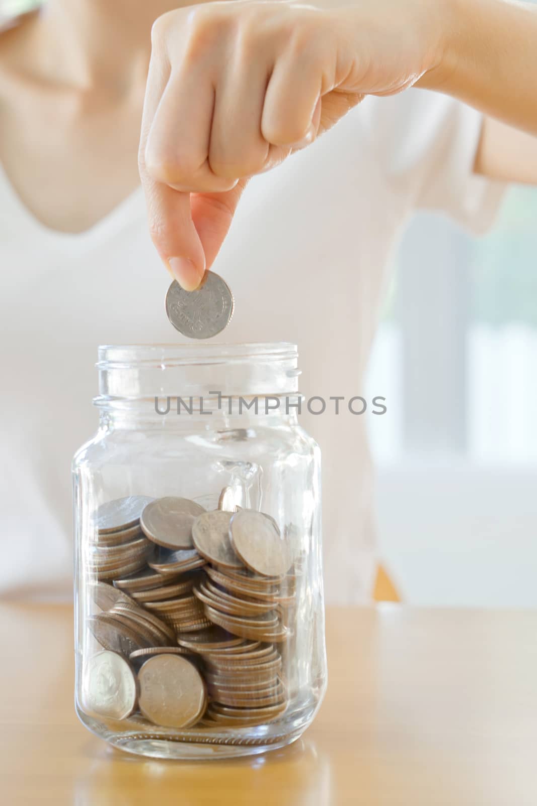 Woman hands with coins in glass jar, close up