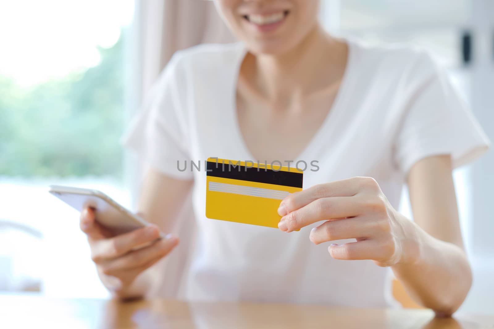 Close-up woman's hands holding a credit card and using cell phone for online shopping