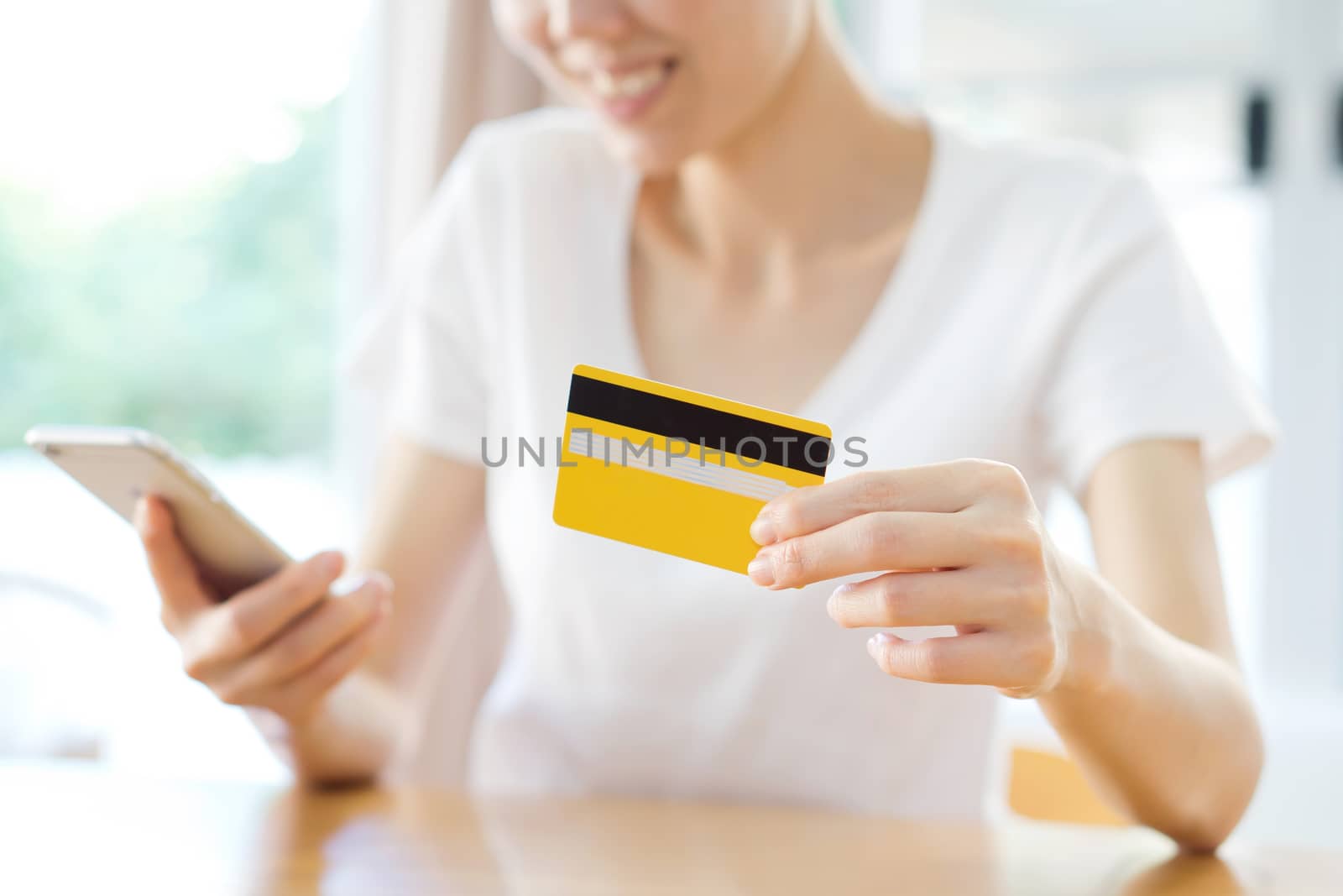 Happy woman shopping online with a credit card and a phone 