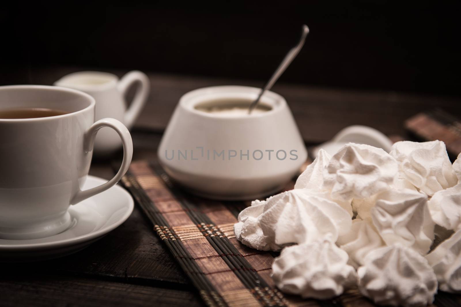 bizet on a brown wooden table with a cup of tea, sugar and milk