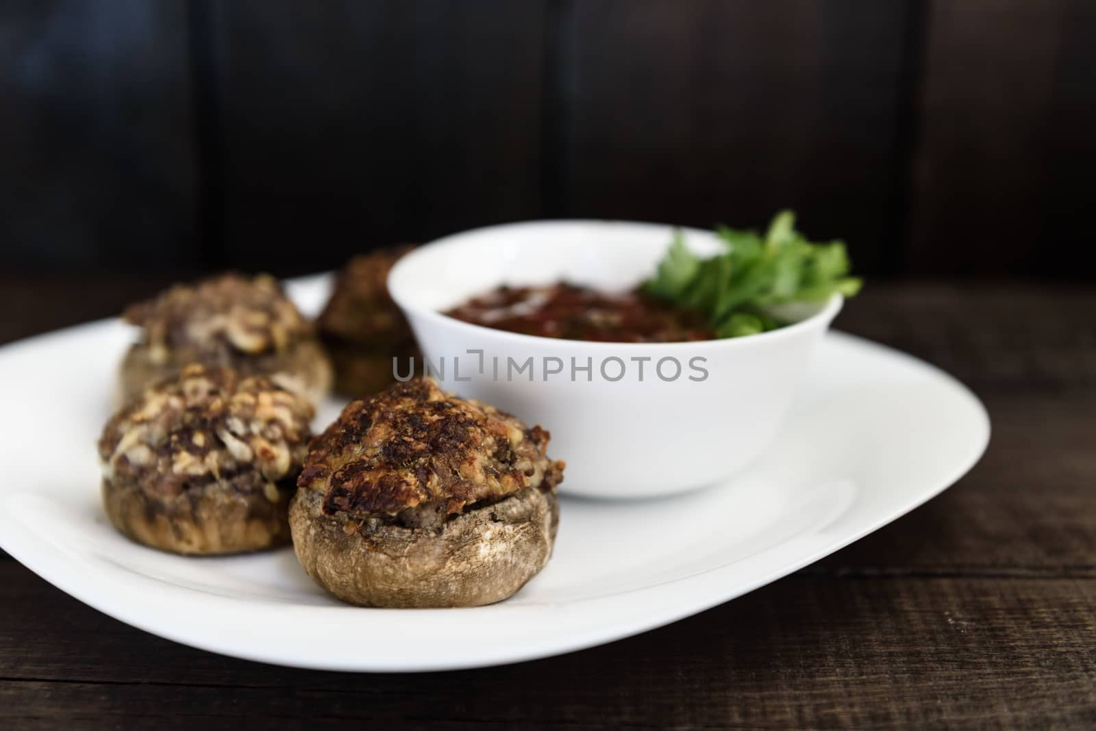 baked mushrooms with meat and sauce on a plate and wood