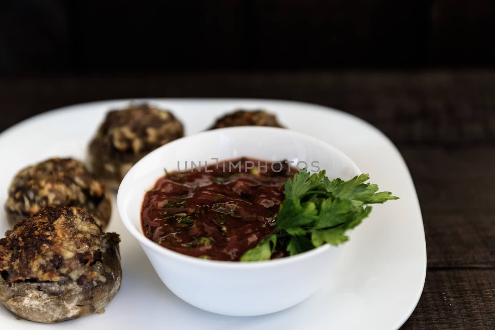 baked mushrooms with meat and sauce on a plate and wood