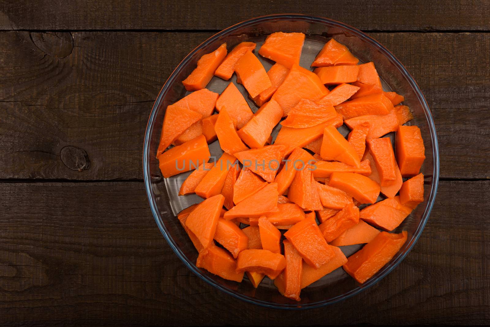 sweet baked pumpkin chopped lomikami in glass dish on wooden background