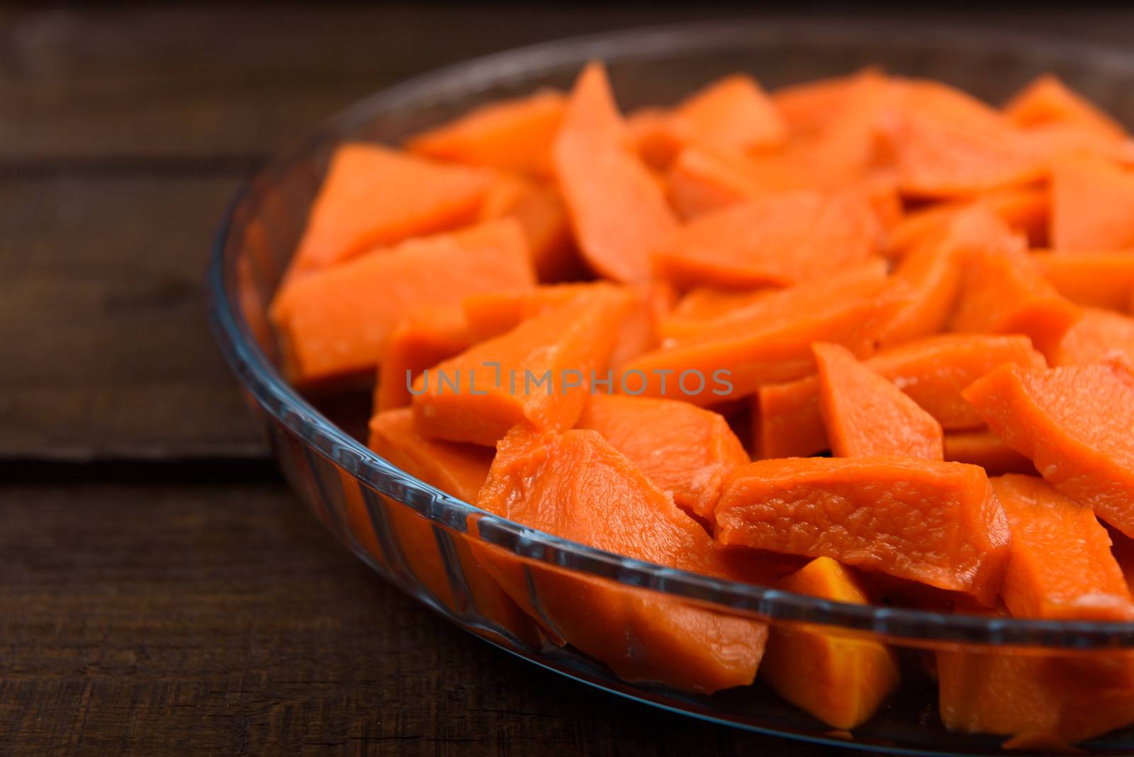 sweet baked pumpkin chopped lomikami in glass dish on wooden background