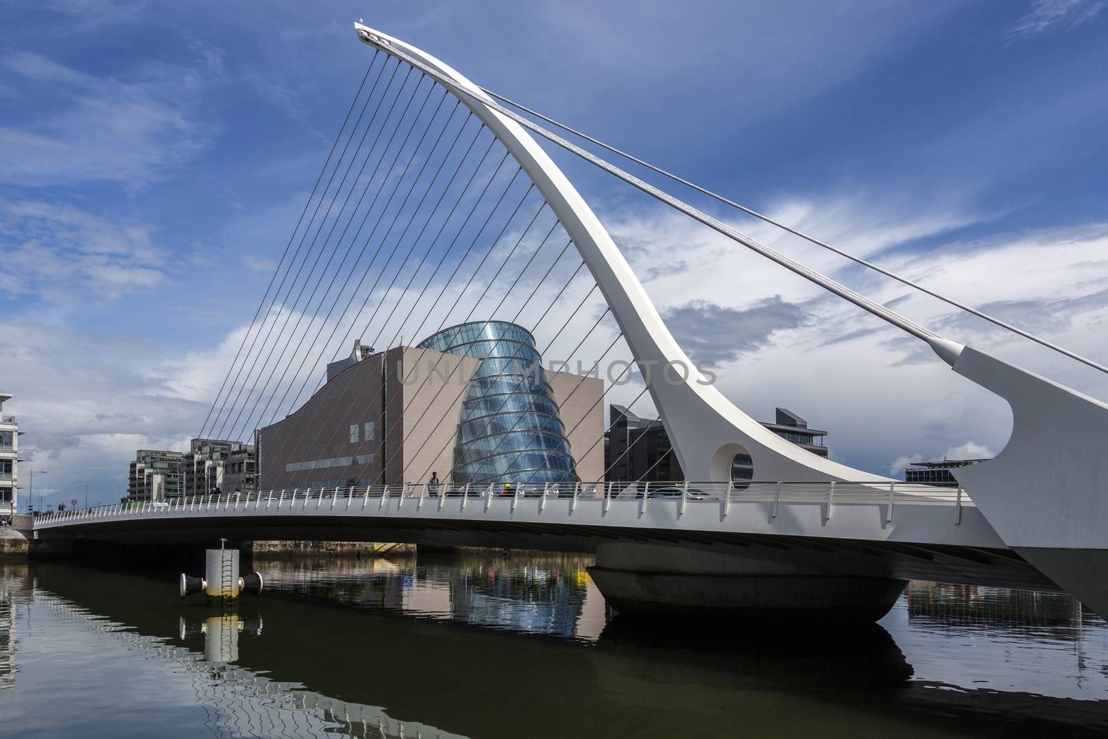 The Samuel Beckett Bridge and the building on the waterfront near the Convention Center - Dublin city center in the republic of Ireland. This is a cable-stayed bridge that joins Sir John Rogerson's Quay on the south side of the River Liffey to Guild Street and North Wall Quay in the Docklands area. The innovative architect Santiago Calatrava designed this and a number of other bridges and buildings in Ireland. The Dublin Convention Centre can also be seen in the background. It was designed by the American-Irish architect Kevin Roche.