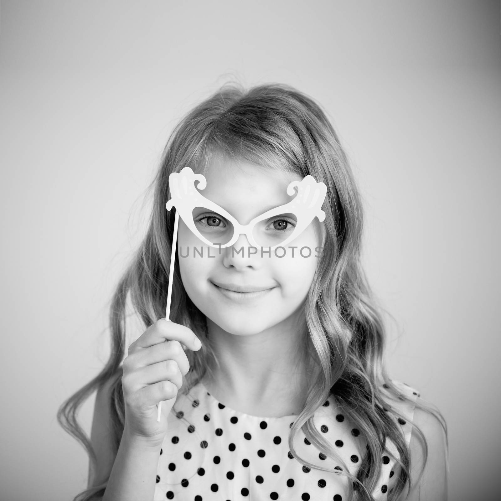 Black and white photography of a lovely little girl with funny party paper glasses or mask