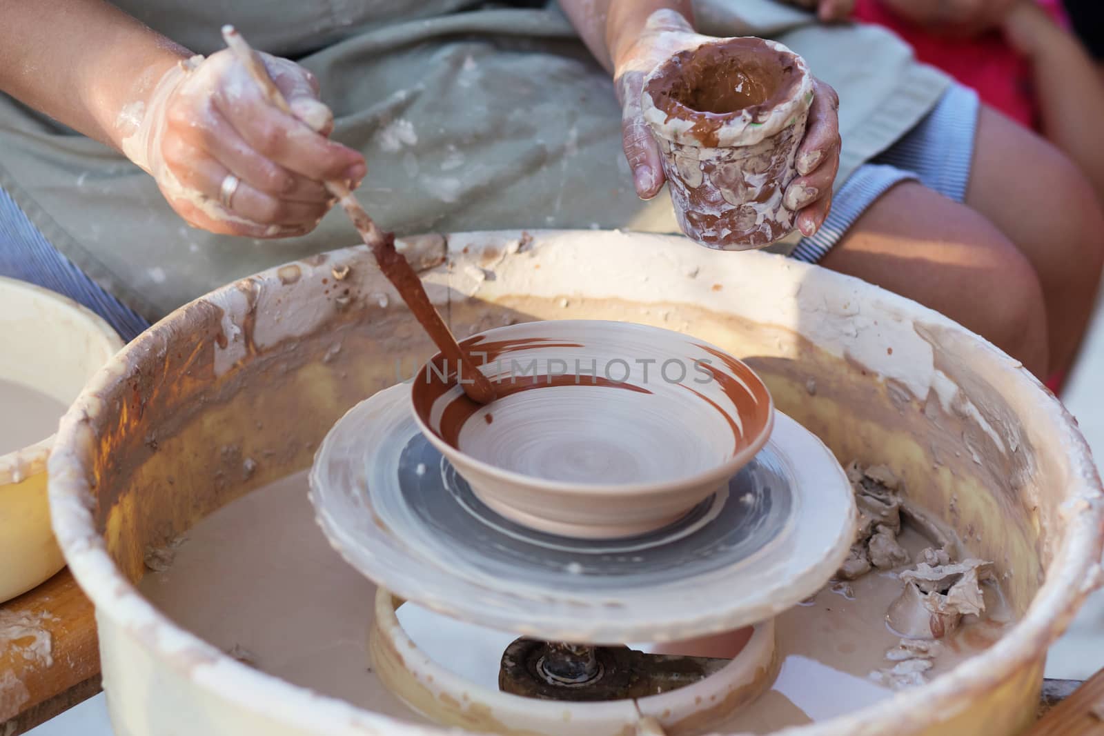 Hands of girl potter, creating an earthen jar on the circle, close-up