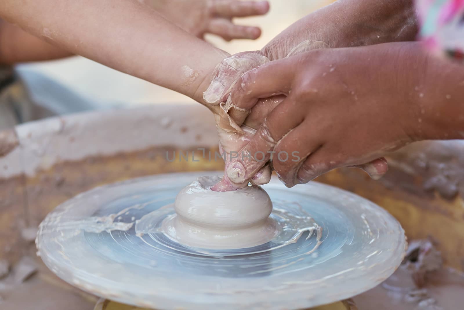 Hands of young potter, creating an earthen jar on the circle, close-up