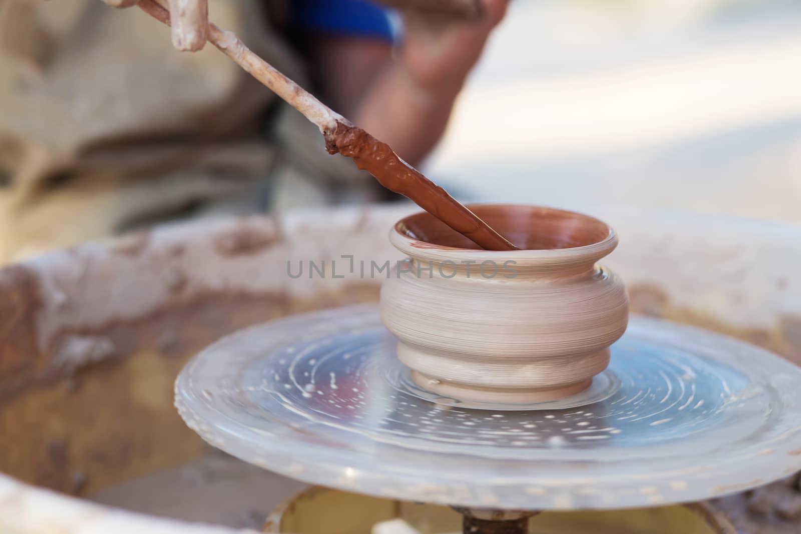 Hands of young potter, creating an earthen jar on the circle, close-up