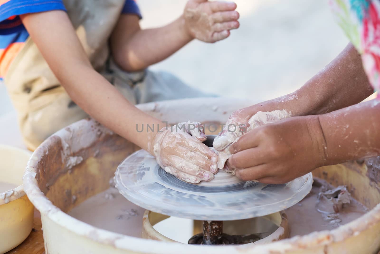 Hands of young potter, creating an earthen jar on the circle, close-up