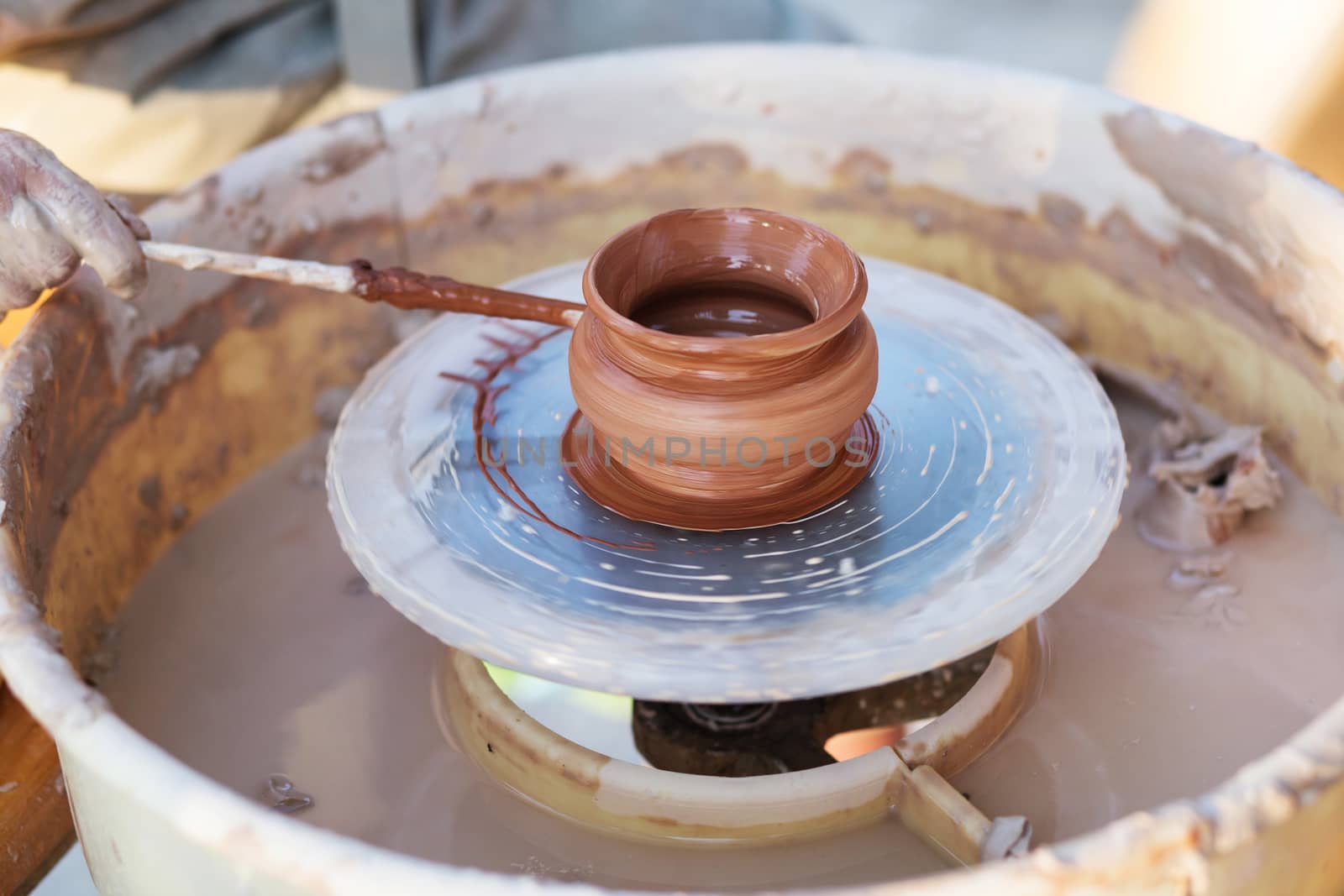 Hands of young potter, creating an earthen jar on the circle, close-up