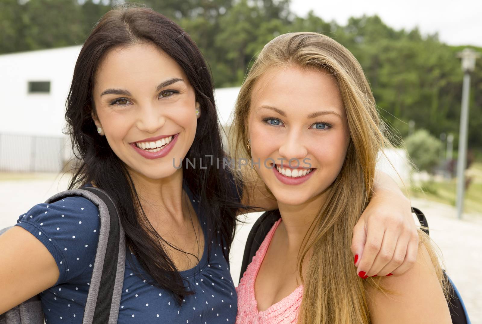 Two beautiful and happy teenage students smiling 