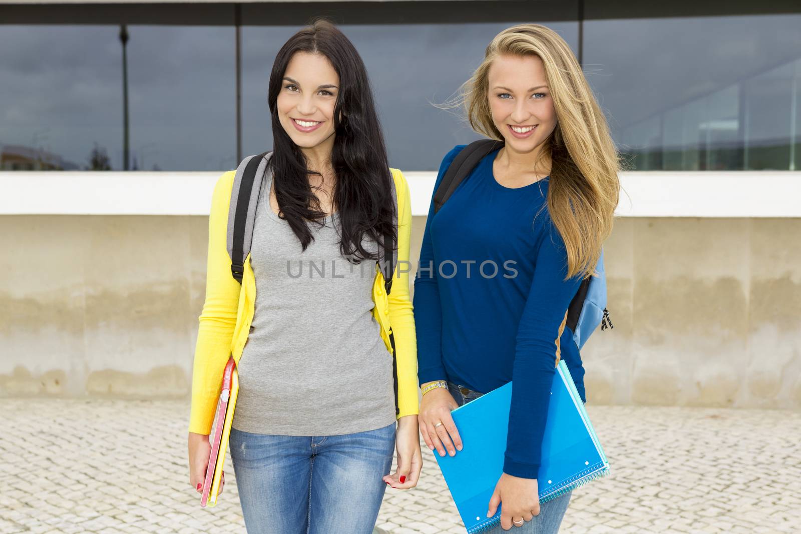 Two happy and beautiful teenage students in the school 