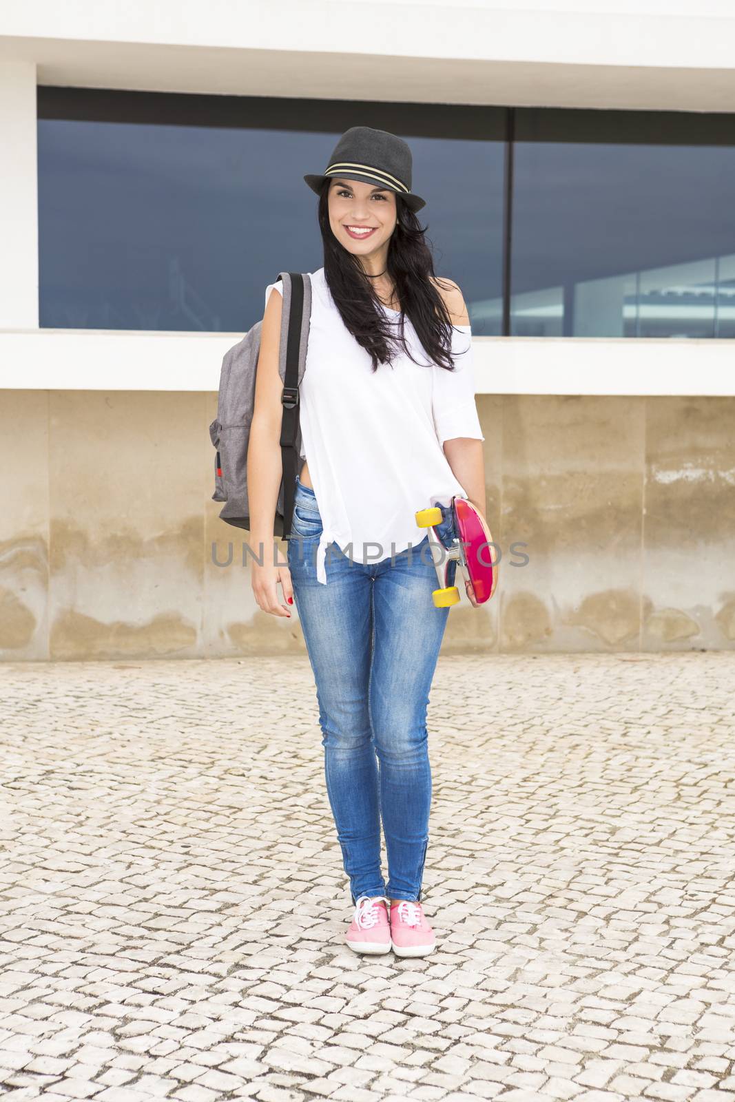 Beautiful and happy student in the school holding a skate