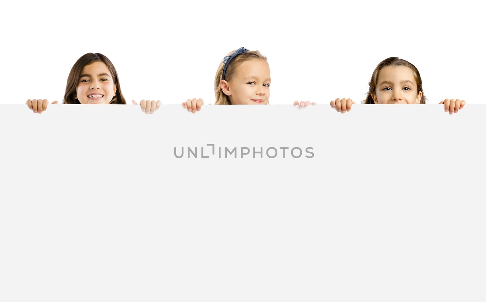 Cute litle girls holding a big white board with copyspace.