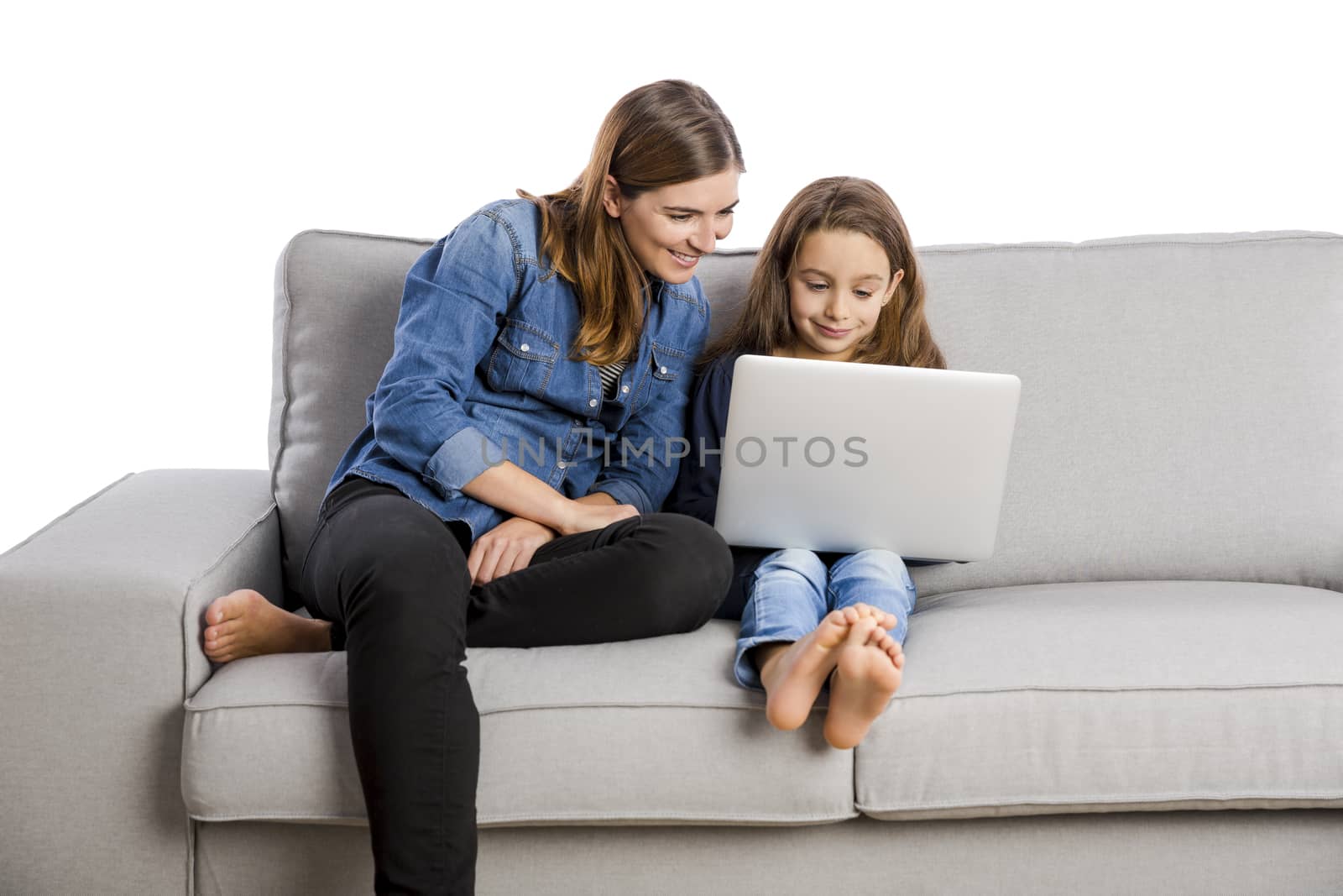 Mother teaching her little daughter working with a laptop