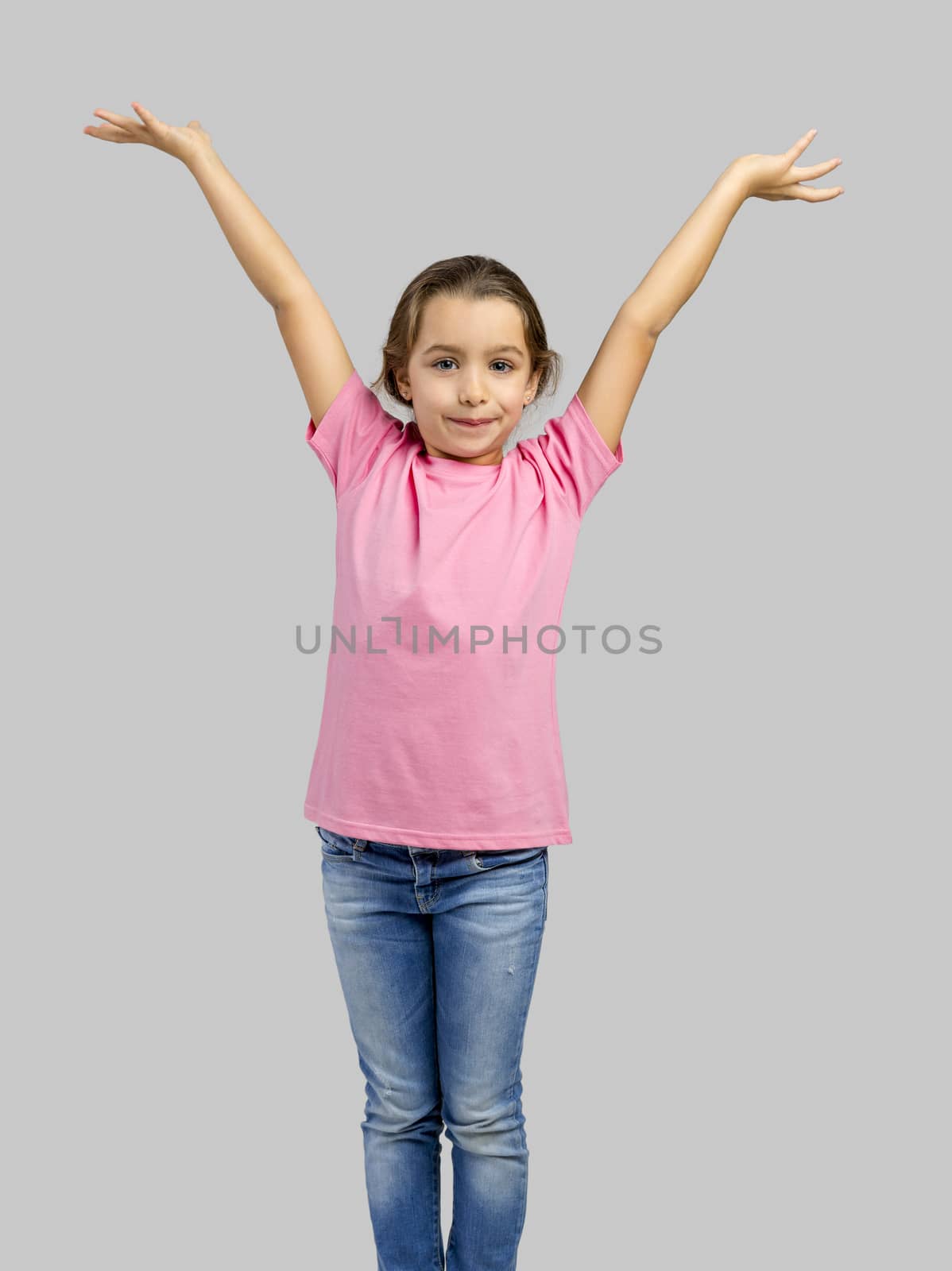 Studio portrait of a happy little girl with arms raised on air