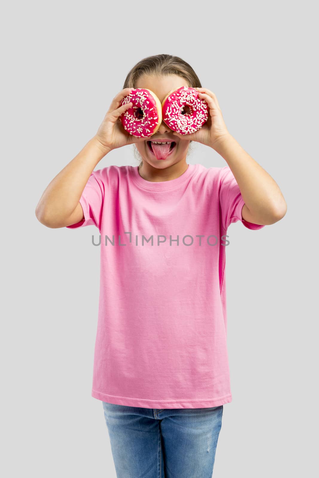 Studio portrait of a beautiful little girl looking through a donut