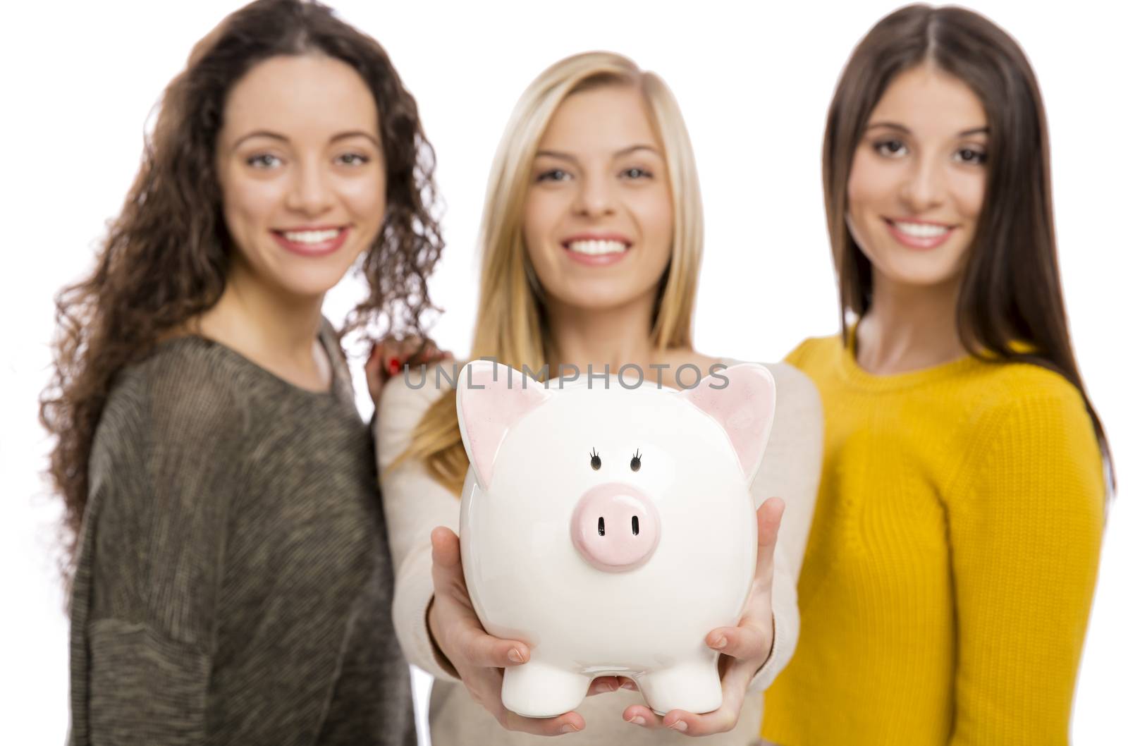 Studio portrait of three teenage girls holding a piggybank