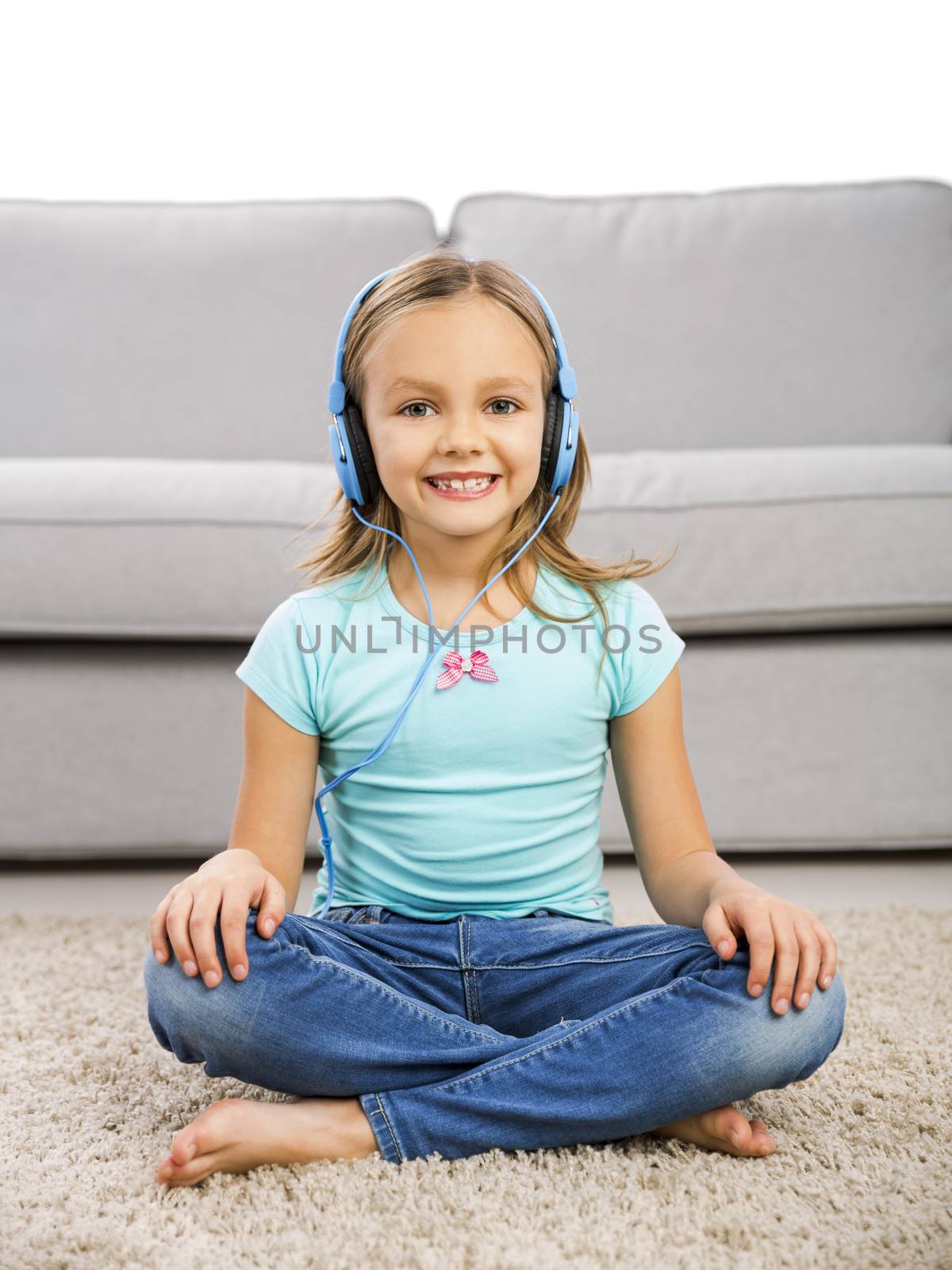 Little blonde girl at home listen music with headphones