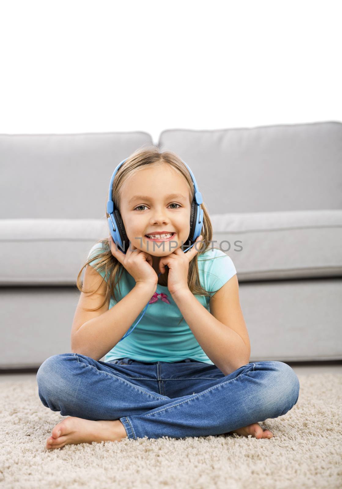 Little blonde girl at home listen music with headphones