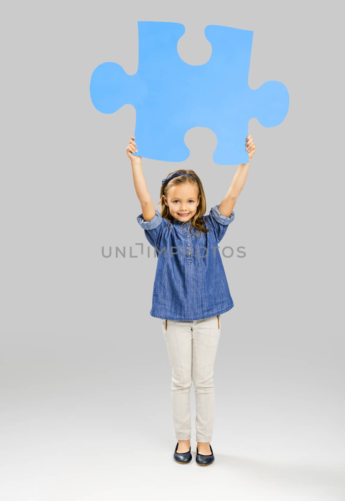 Beautiful little girl holding a big blue Puzzle