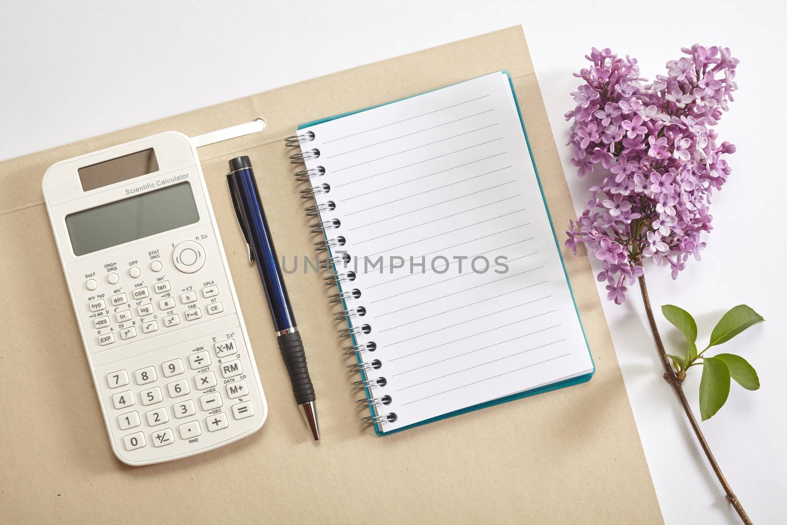 Top view office workplace - calculator, pen, flower and notebook on white table
