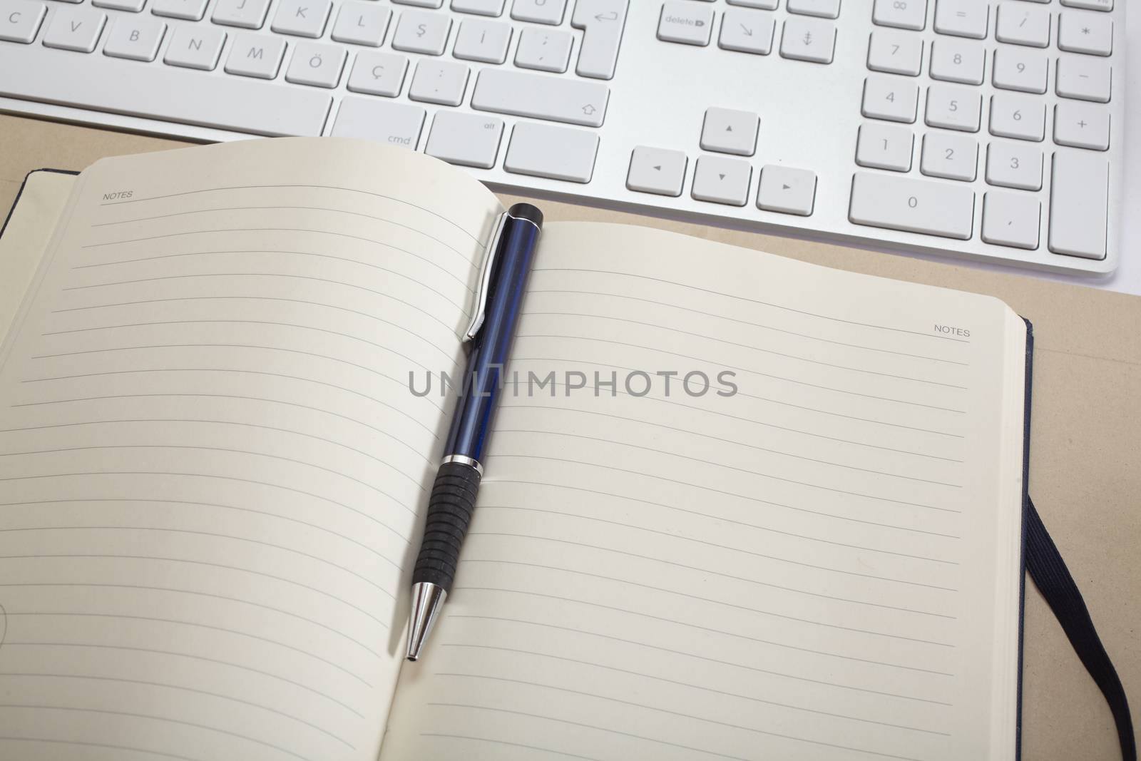 Top view office workplace - keyboard, pen and notebook on white table