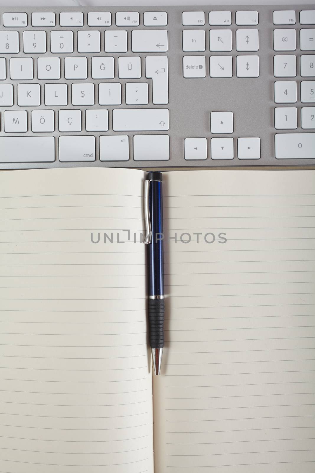 Top view office workplace - keyboard, pen and notebook on white table