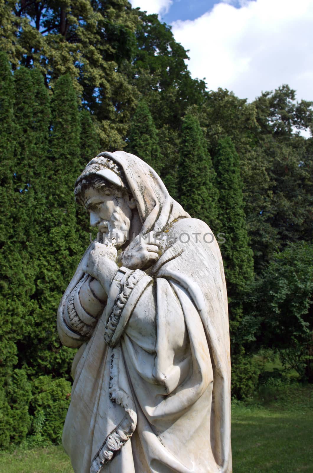 Marble park sculpture of an old man freezing and wrapped into coverlets personifying the cold season of the year. The palace and park complex Manor Tarnowski, s.Kachanovka, Ukraine