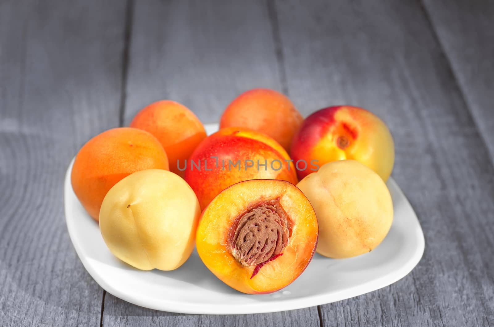 Southern fruit, apricots and nectarines in a plate on a gray-blue wooden background