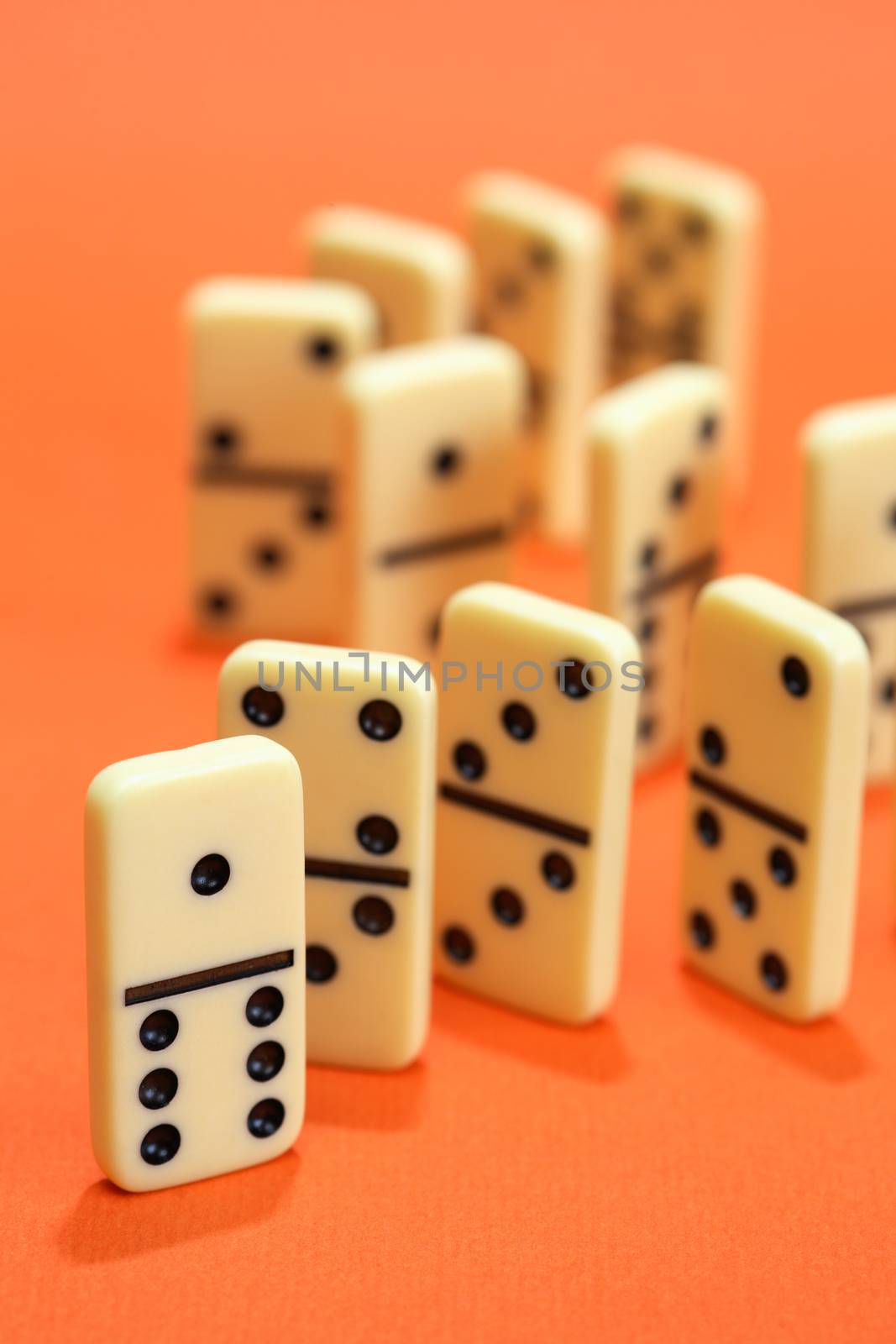 Black dominoes standing in a row on red background